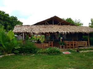 a hut with a straw roof with a table and chairs at SEE-KEE-HOR Cafe and Hostel in Siquijor