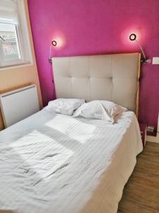 een slaapkamer met een wit bed en een roze muur bij La Petite Maison in Brest