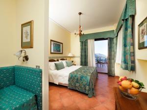 a hotel room with a bed and a chair and a window at Hotel Sirius in Taormina