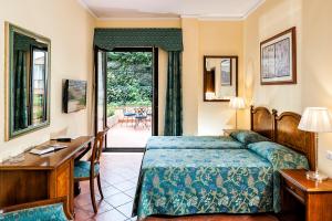een hotelkamer met een bed, een bureau en een slaapkamer bij Hotel Sirius in Taormina