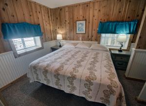 a bedroom with a bed and two windows with blue curtains at Outer Banks Motel - Village Accommodations in Buxton