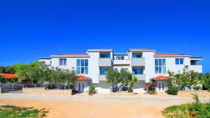 a large white building with trees in front of it at Apartment PASMAN - appartement 50 m2 et piscine in Pakoštane