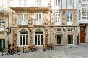 a building with tables and chairs in front of it at Hostal Pórtico in Betanzos