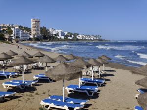 a beach with chairs and umbrellas and the ocean at Calahonda Buenavista in Mijas Costa