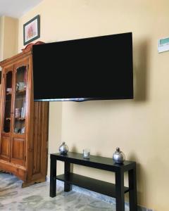 TV de pantalla plana colgada en una pared con mesa en El Rico Rincón de Sanlúcar la Mayor, en Sanlúcar la Mayor