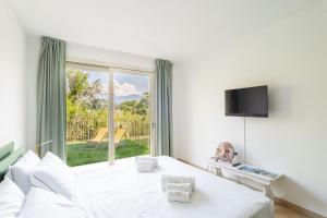 a white bedroom with a bed and a window at Como Lake Nest - Studio with garden in Tremezzo