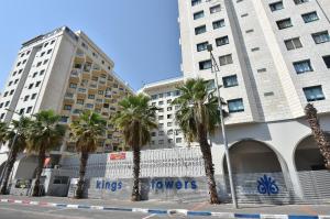 a row of palm trees in front of two tall buildings at Boutique Lake Kinneret Apartment in Tiberias