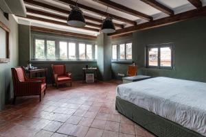 a bedroom with a bed and two chairs and windows at La Locanda di Grazzano Visconti in Grazzano Visconti