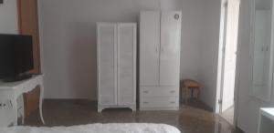 a white bedroom with a dresser and a tv at Habitaciones amplias en el Centro de Granada in Granada