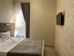 um quarto com uma cama, uma televisão e uma janela em Maro Hotel em Sochi