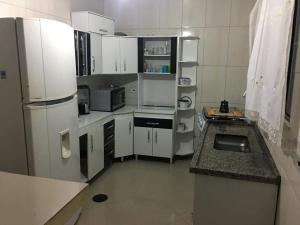 a small kitchen with white cabinets and a refrigerator at Casa com ar condicionado e 2 suítes ilha comprida in Ilha Comprida
