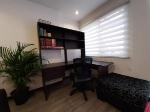 een slaapkamer met een bureau en een stoel en een plant bij Moderno departamento en Condominio Providencia in Cuenca