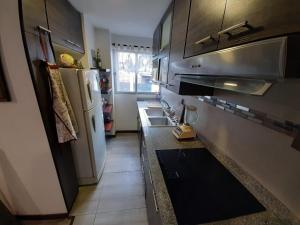 a small kitchen with a refrigerator and a sink at Moderno departamento en Condominio Providencia in Cuenca