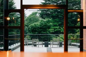 an open door to a patio with chairs and trees at HOTEL KARUIZAWA CROSS in Karuizawa