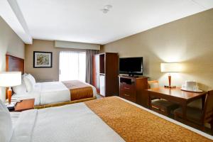 a hotel room with a bed, tv, chair, desk and television at Quality Inn - Kitchener in Kitchener