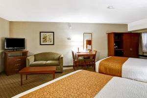a hotel room with two beds and a chair and a table at Quality Inn - Kitchener in Kitchener
