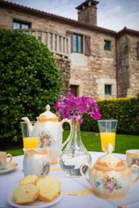 a table with tea pots and cookies and a vase with flowers at Casa de Barreiro in Teijeiro