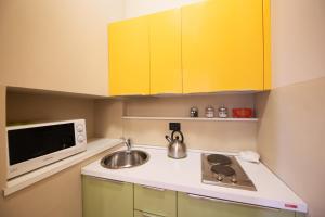 uma pequena cozinha com armários amarelos e um lavatório em Magenta Collection Crociferi 3 em Roma