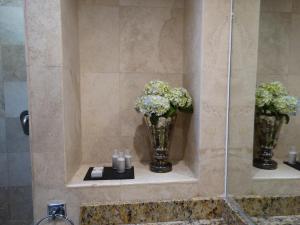 Baño con 2 jarrones con flores y velas en Hotel Amberes en Querétaro