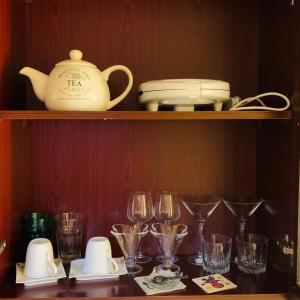 a shelf with glasses and a teapot and cups at Wait N Sea !! Sea View Studio Ras Al Khaimah in Ras al Khaimah