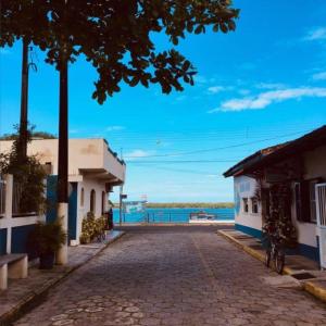 a cobblestone street next to two buildings and the ocean at Residencial Beira Mar Cananéia in Cananéia