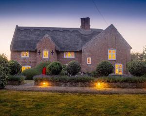 a large brick house with lights in the yard at Old Hall Country Breaks in Tilney All Saints
