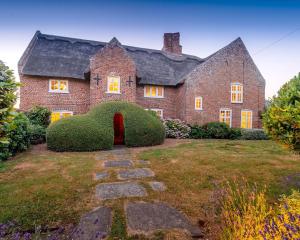 a large brick house with a large hedge in the yard at Old Hall Country Breaks in Tilney All Saints
