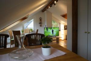 een eetkamer met een tafel met een vaas en een tv bij Ferienwohnung Ahrtalblick in Sinzig