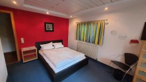 1 dormitorio con 1 cama con pared roja en Chalet Landhaus Einsiedler, en Sankt Gallenkirch