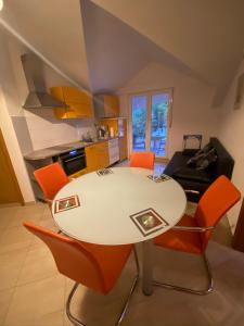 a kitchen with a white table and orange chairs at Apartments Grozdana in Gradac