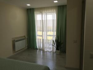 a bedroom with a large window with green curtains at Квартира город Умань in Umanʼ