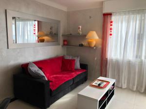 Cannes Les Pins في كان: غرفة معيشة مع أريكة حمراء ومرآة