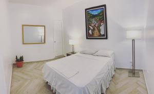 a white bedroom with a bed and a painting on the wall at Palmira Hostel in Tegucigalpa