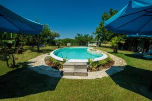 a swimming pool in a yard with an umbrella at Casale Bavi in Ortona