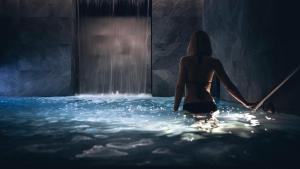 a woman standing in the water in front of a waterfall at Le Parc Hôtel Obernai & Yonaguni Spa in Obernai