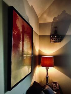 a lamp sitting next to a wall with a picture at Gite Hotel de maître centre village la Chapelle in Lyons-la-Forêt