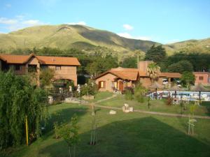 une grande cour avec une maison et des montagnes en arrière-plan dans l'établissement Cabañas El Eden Spa, à La Falda