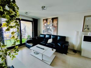 een woonkamer met een zwarte bank en een salontafel bij NON STRESS Ático Dúplex con vistas al MAR in Valencia