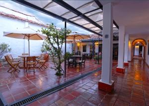 een patio met tafels, stoelen en parasols bij Hotel Don Paulino in Villa de Leyva