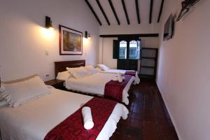 a hotel room with two beds and two windows at Hotel Don Paulino in Villa de Leyva