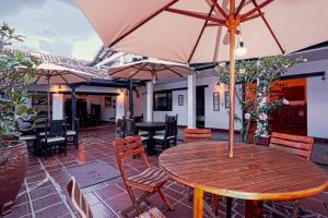 een houten tafel met een parasol op een patio bij Hotel Don Paulino in Villa de Leyva