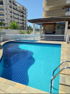 a swimming pool with blue water in front of a building at VARANDA GOURMET c churrasqueira-3 quartos- Wi-fi in Bertioga