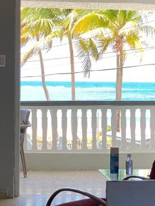 a balcony with a view of the ocean and palm trees at Cozy Beach Apartment in Luquillo
