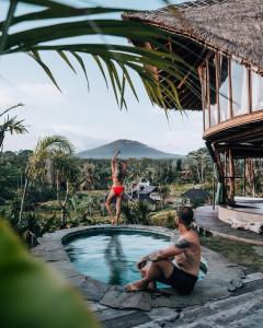 a woman standing on the edge of a swimming pool in a resort at Veluvana Bali in Sidemen