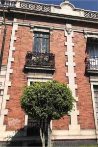 een rood bakstenen gebouw met een boom ervoor bij Casa Turin in Mexico-Stad