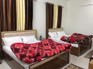 Duas camas num quarto com cobertores vermelhos em Corridor inn em Derā Nānak