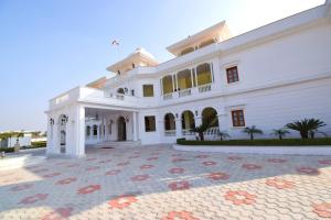 een groot wit huis met een grote binnenplaats bij Umaid Farm Resort- A Legancy Vintage Stay In Jaipur in Jaipur