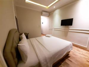 a bedroom with a bed and a flat screen tv at Flamboyan Residence Cipete in Jakarta