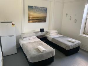 a room with two beds and a refrigerator at Sandy Bottoms Guesthouse in Sydney