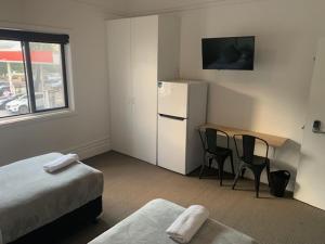 Camera con letto, tavolo e frigorifero. di Sandy Bottoms Guesthouse a Sydney